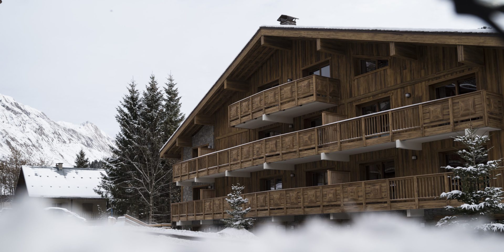 MGM Le Roc des Tours Le Grand Bornand Chinaillon Frankrijk wintersport skivakantie luxe buiten façade hout balkons sneeuw bergen uitzicht