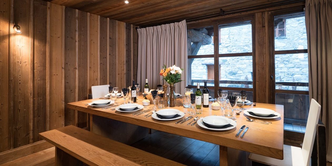 Chalet Farmhouse Val d'Isere Tignes-Val d'Isere Frankrijk wintersport skivakantie luxe eetkamer gedekte tafel bloemen wijn houten banken hout