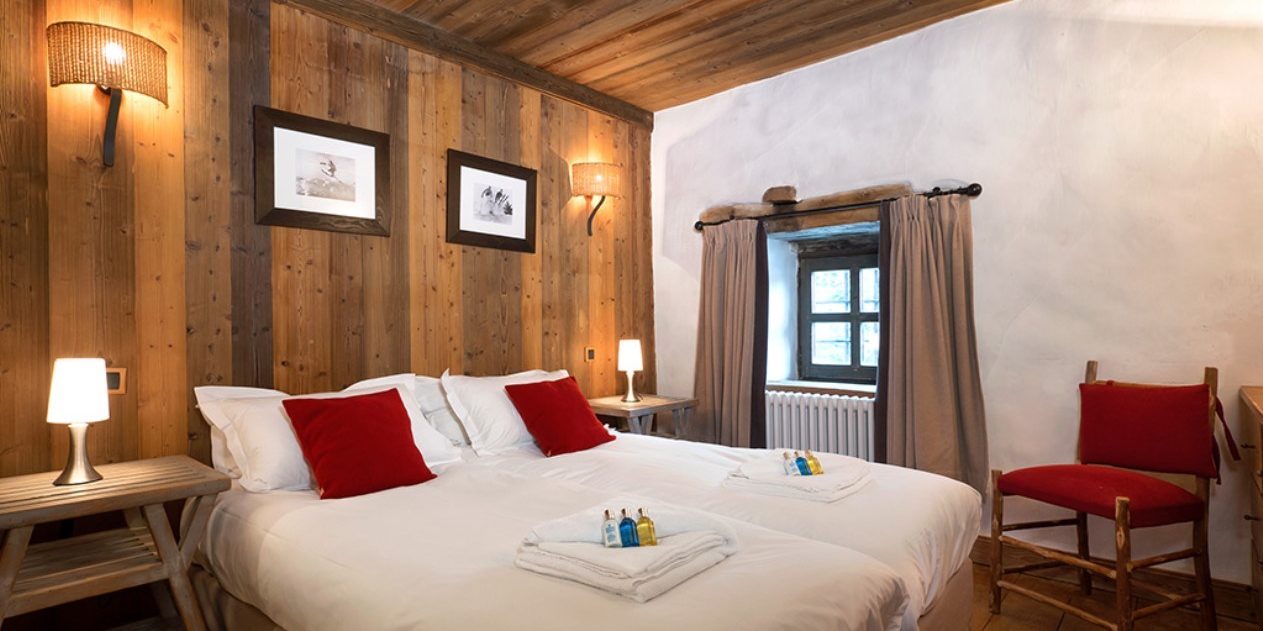 Chalet Farmhouse Val d'Isere Tignes-Val d'Isere Frankrijk wintersport skivakantie luxe slaapkamer rode kussens rode stoel raam