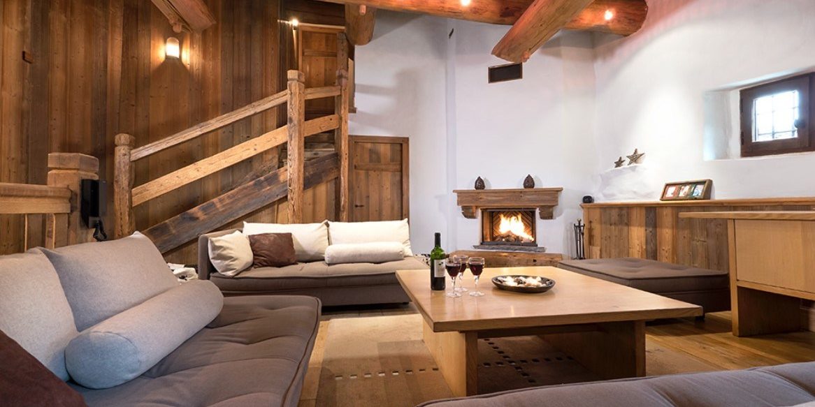 Chalet Farmhouse Val d'Isere Tignes-Val d'Isere Frankrijk wintersport skivakantie luxe living banken kussens open haard wijn wijnglazen hocker trap