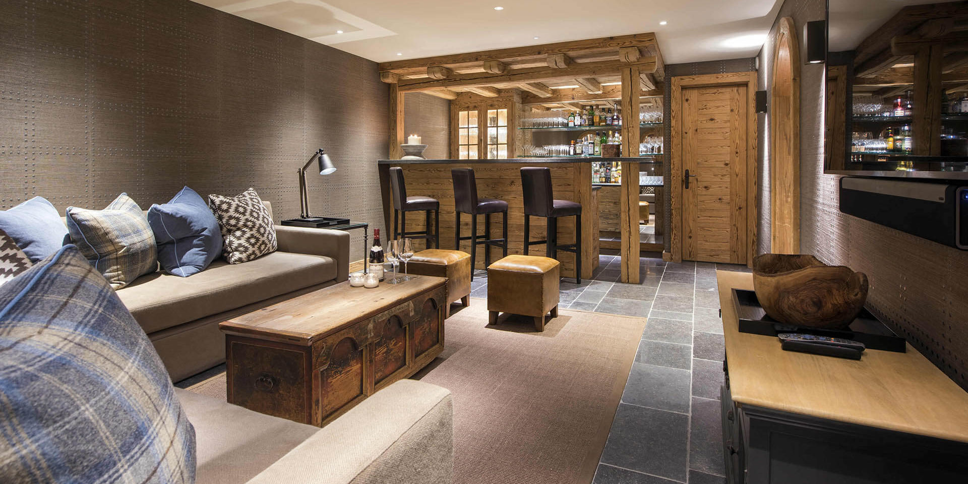 Chalet Chouqui Verbier Les 4 Vallees Zwitserland wintersport skivakantie luxe TV kamer banken kussens salontafel wijn wijnglazen bar barkrukken dranken