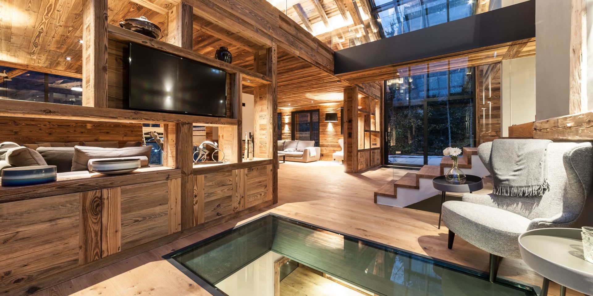 Chalet Joux Plane Morzine Les Portes du Soleil Frankrijk wintersport skivakantie luxe TV kamer fauteuil tafeltje glazen plaat kast trap raam uitzicht bank verlichting