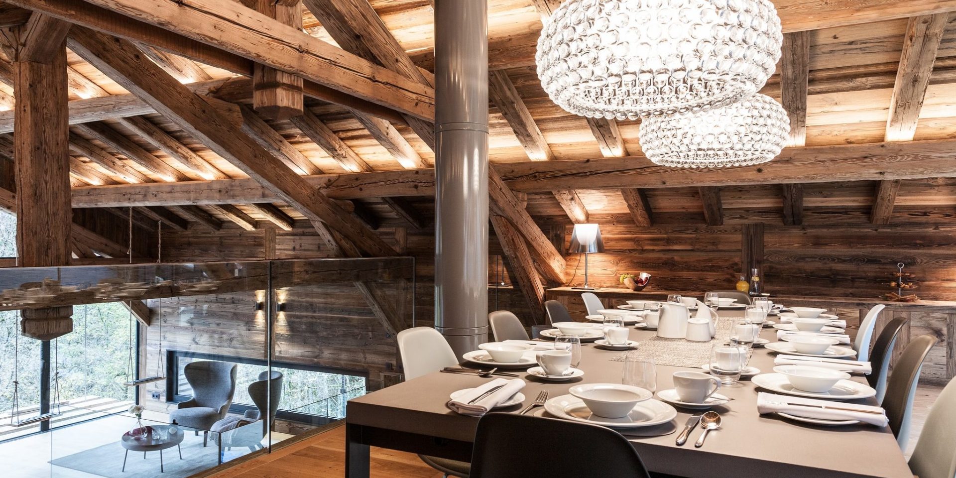 Chalet Joux Plane Morzine Les Portes du Soleil Frankrijk wintersport skivakantie luxe mezzanine eetkamer gedekte tafel grote lampen fauteuils schommels ramen houten balken