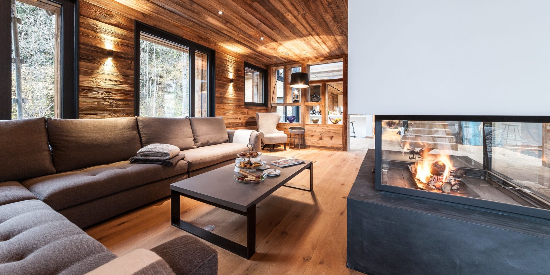 Chalet Joux Plane Morzine Les Portes du Soleil Frankrijk wintersport skivakantie luxe living open naard hoekbank kleden salontafel high tea fauteuil hout ramen
