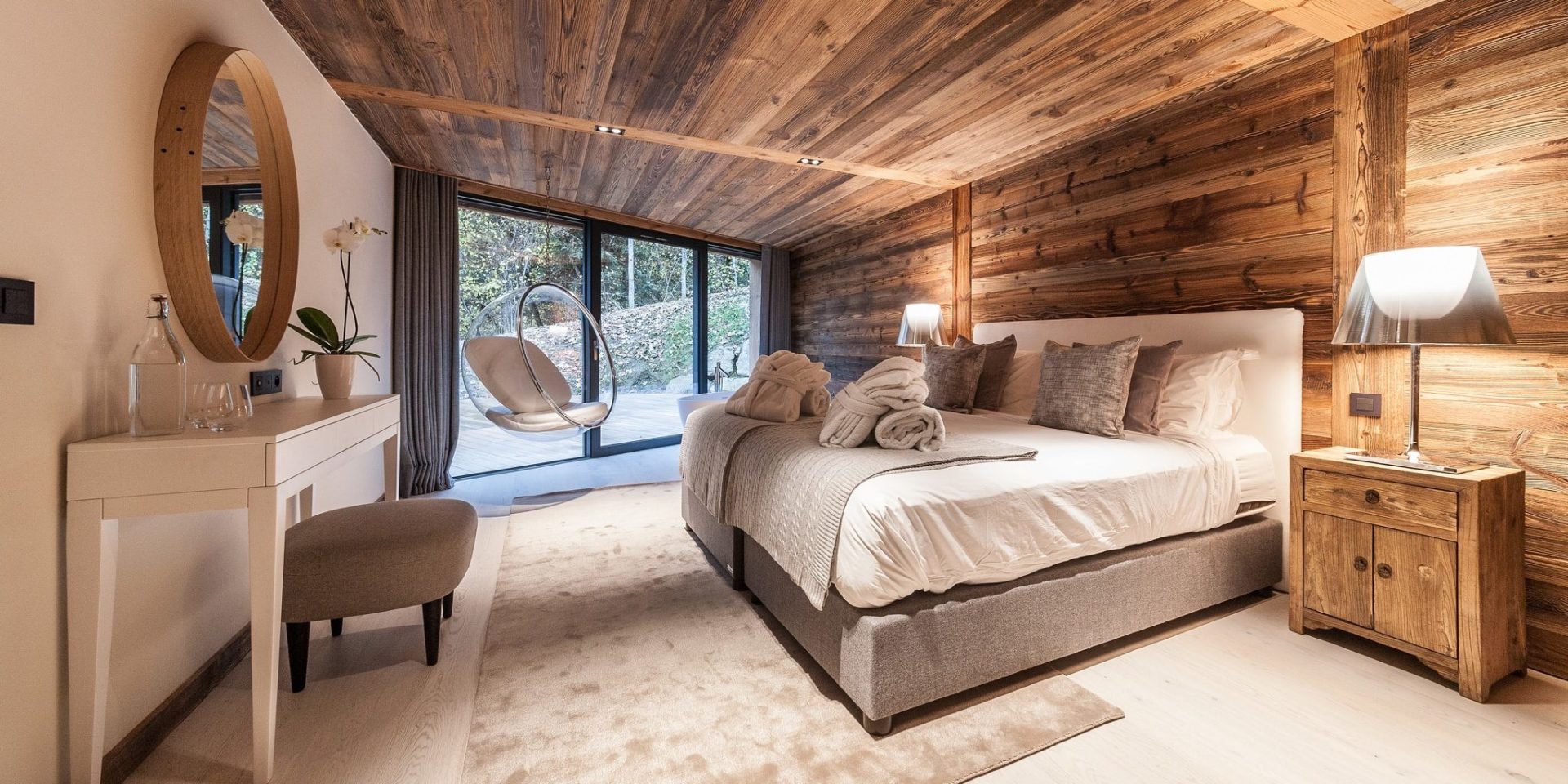 Chalet Joux Plane Morzine Les Portes du Soleil Frankrijk wintersport skivakantie luxe slaapkamer 2-persoonsbed nachtkastje hangende stoel lamp bureau kruk plant spiegel raam terras hout