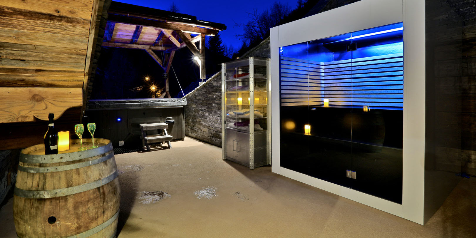 Chalet Quezac Tignes Tignes-Val d'Isere Frankrijk wintersport skivakantie luxe sauna hot tub terras wijnvat wijn wijnglazen by night