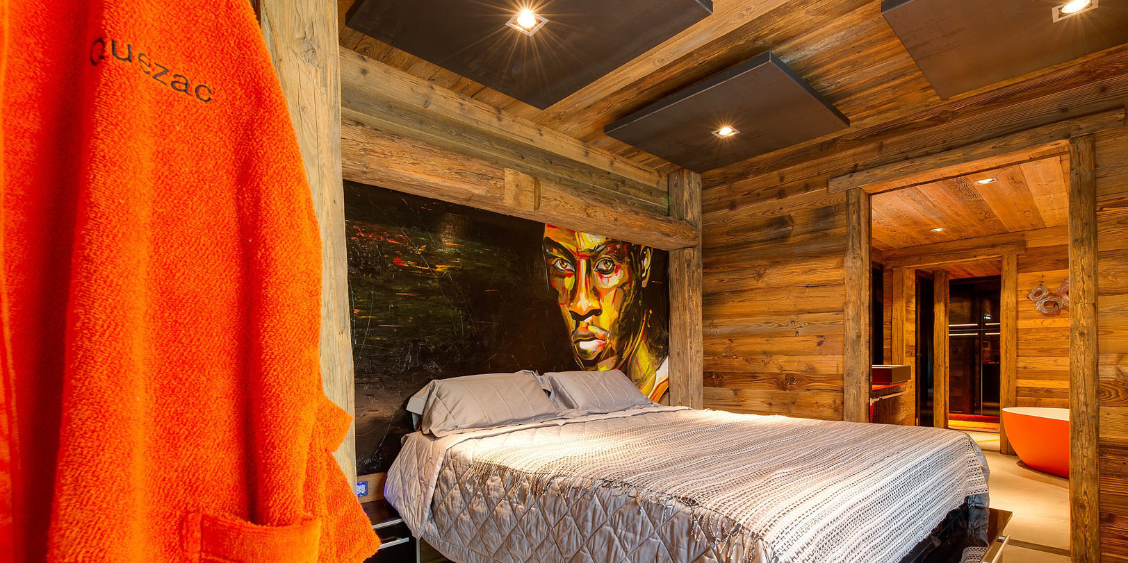 Chalet Quezac Tignes Tignes-Val d'Isere Frankrijk wintersport skivakantie luxe slaapkamer Volcano 2-persoonsbed muurschildering oranje badjas en-suite badkamer oranje bad wastafel hout