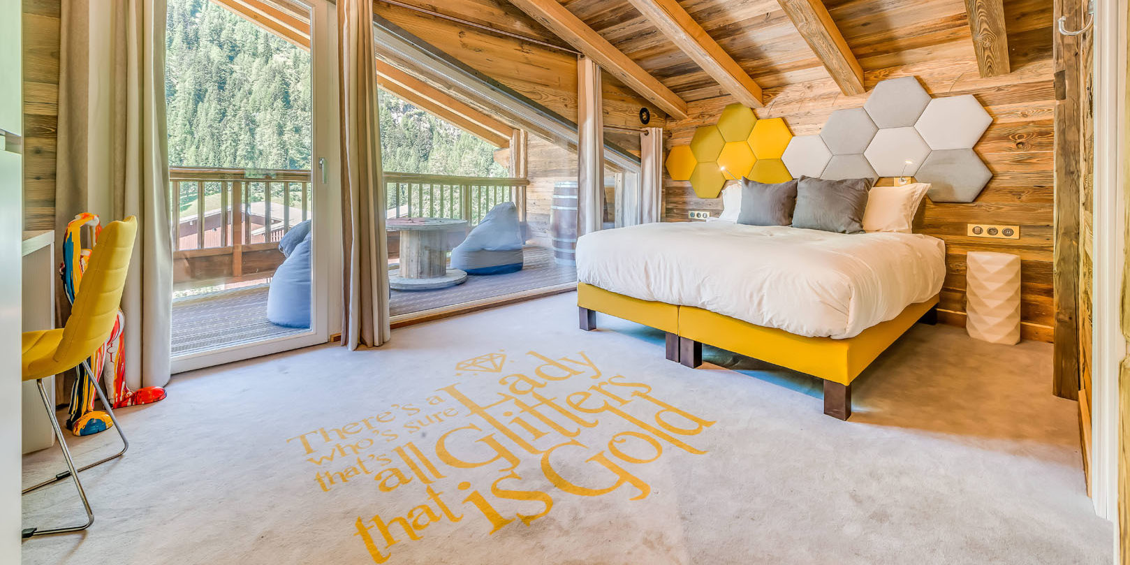 Chalet Rock'n Love Tignes Tignes-Val d'Isere Frankrijk wintersport skivakantie luxe slaapkamer Gold Room 2-persoonsbed bureau gele stoel houten balken terras zitzakken