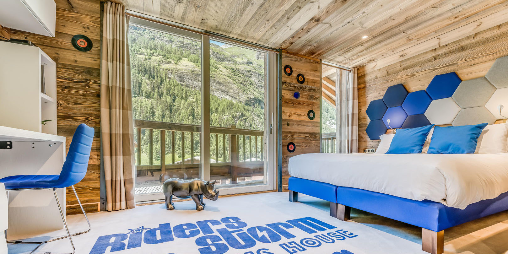 Chalet Rock'n Love Tignes Tignes-Val d'Isere Frankrijk wintersport skivakantie luxe slaapkamer Riders Room 2-persoonsbed neushoorn bureau blauwe stoel lp hout balkon uitzicht bomen