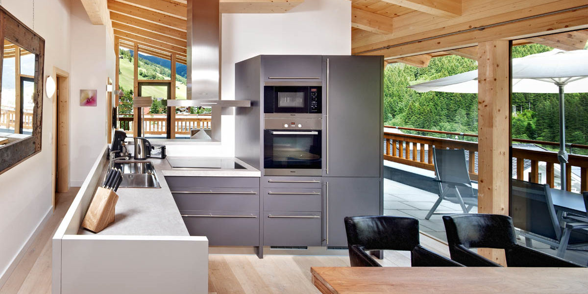 Gerlos Alpine Estate Gerlos Zillertal Arena Oostenrijk wintersport skivakantie luxe appartement keuken eettafel stoelen terras parasol stoelen tafel zitje grote ramen houten balken