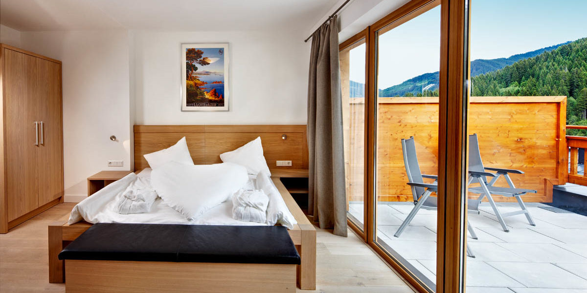 Gerlos Alpine Estate Gerlos Zillertal Arena Oostenrijk wintersport skivakantie luxe slaapkamer 2-persoonsbed kast schuifdeur schilderij terras stoelen bomen