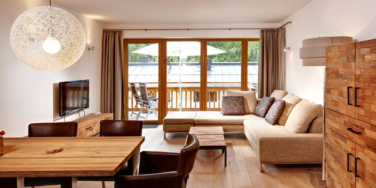 Gerlos Alpine Estate Gerlos Zillertal Arena Oostenrijk wintersport skivakantie luxe appartement eettafel stoelen hoekbank kussens TV kast salontafel balkon stoelen parasol bomen