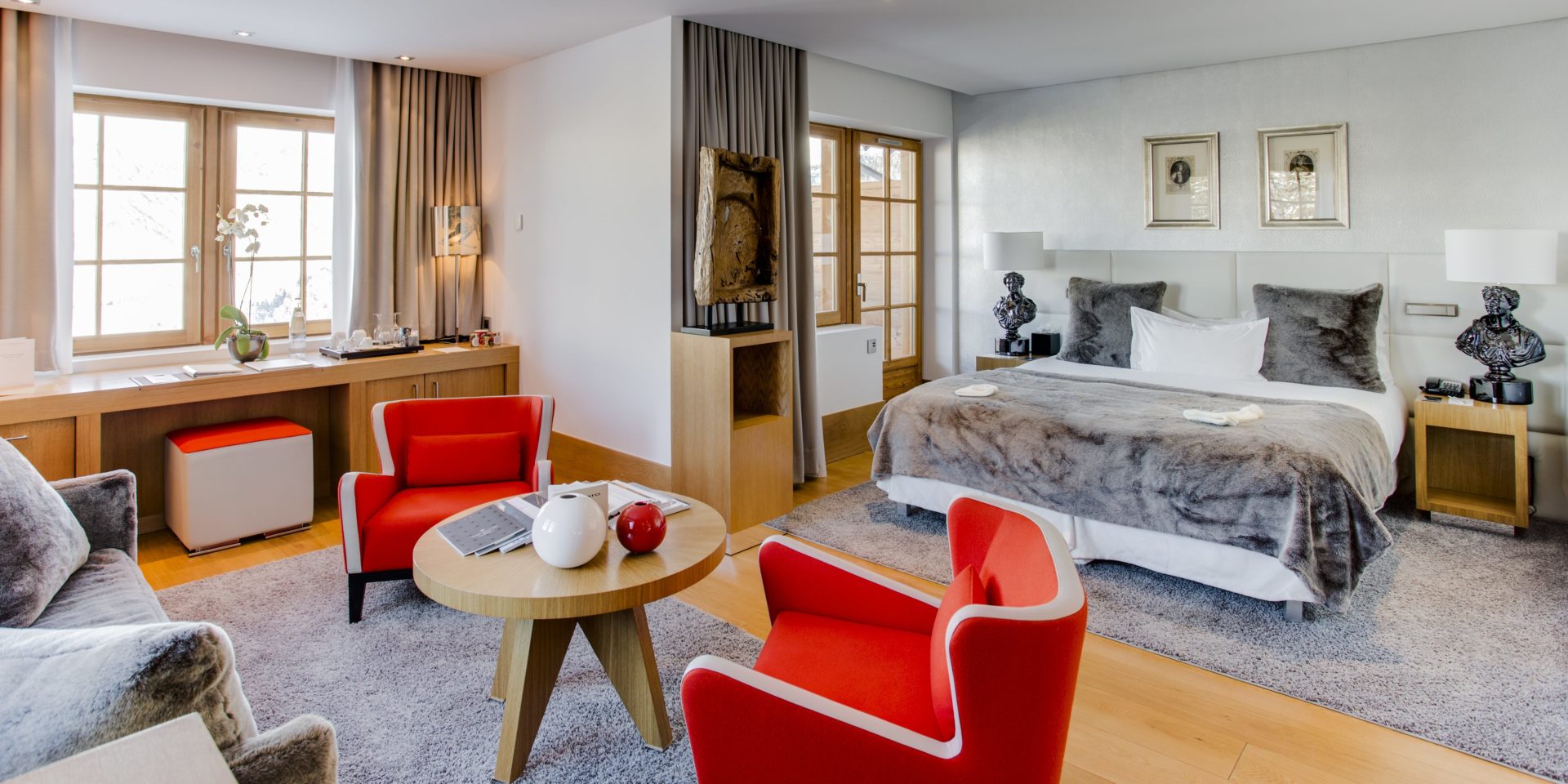 Hotel Le Strato Courchevel 1850 Les 3 Vallees Frankrijk wintersport skivakantie luxe slaapkamer 2-persoonsbed rode fauteuil bank hocker nachtlampjes kleed raam deur