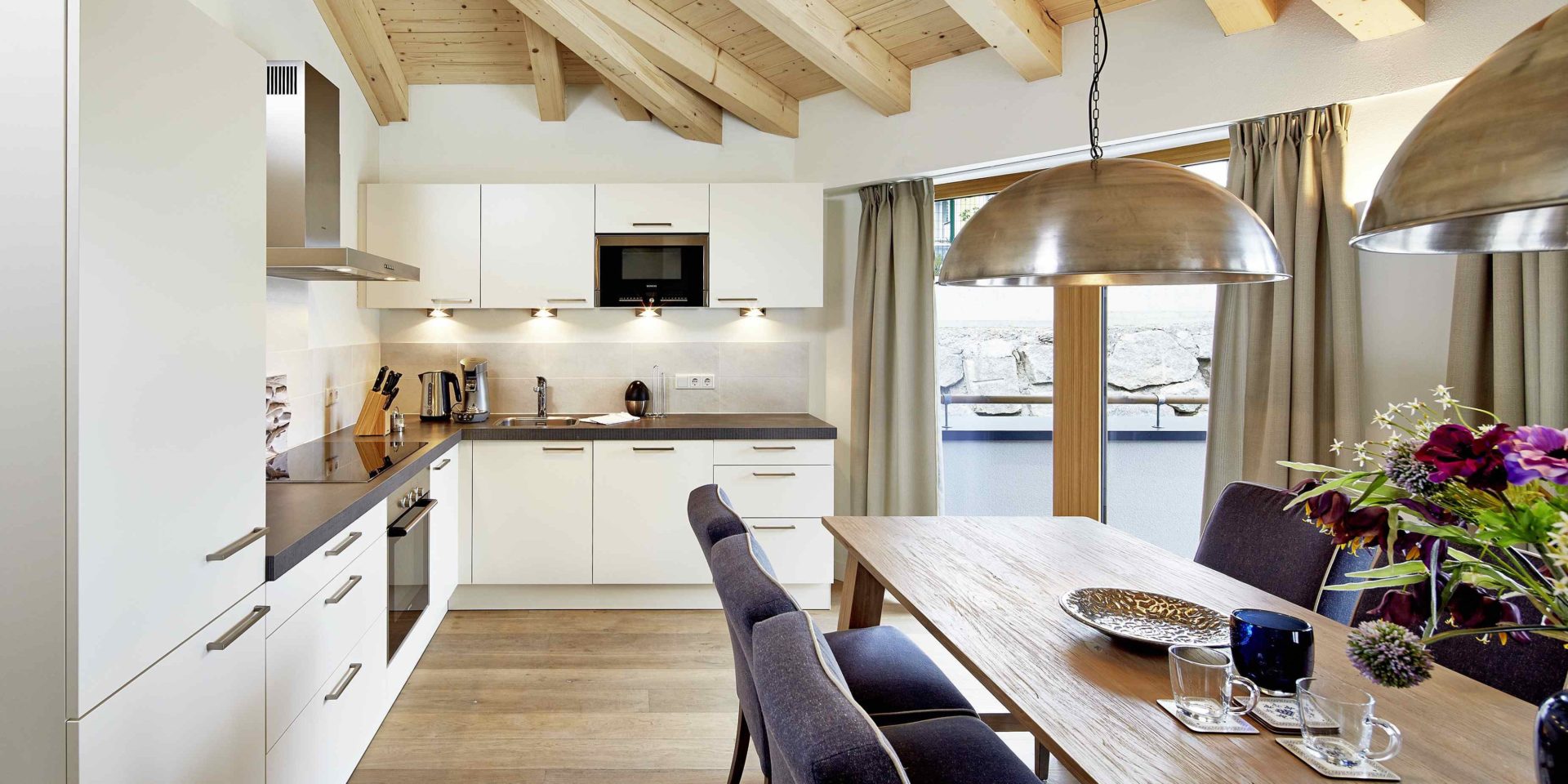 Kaprun Glacier Estate Zell am See-Kaprun Oostenrijk wintersport skivakantie luxe Penthouse K8 eettafel stoelen bloemen lampen keuken houten balken