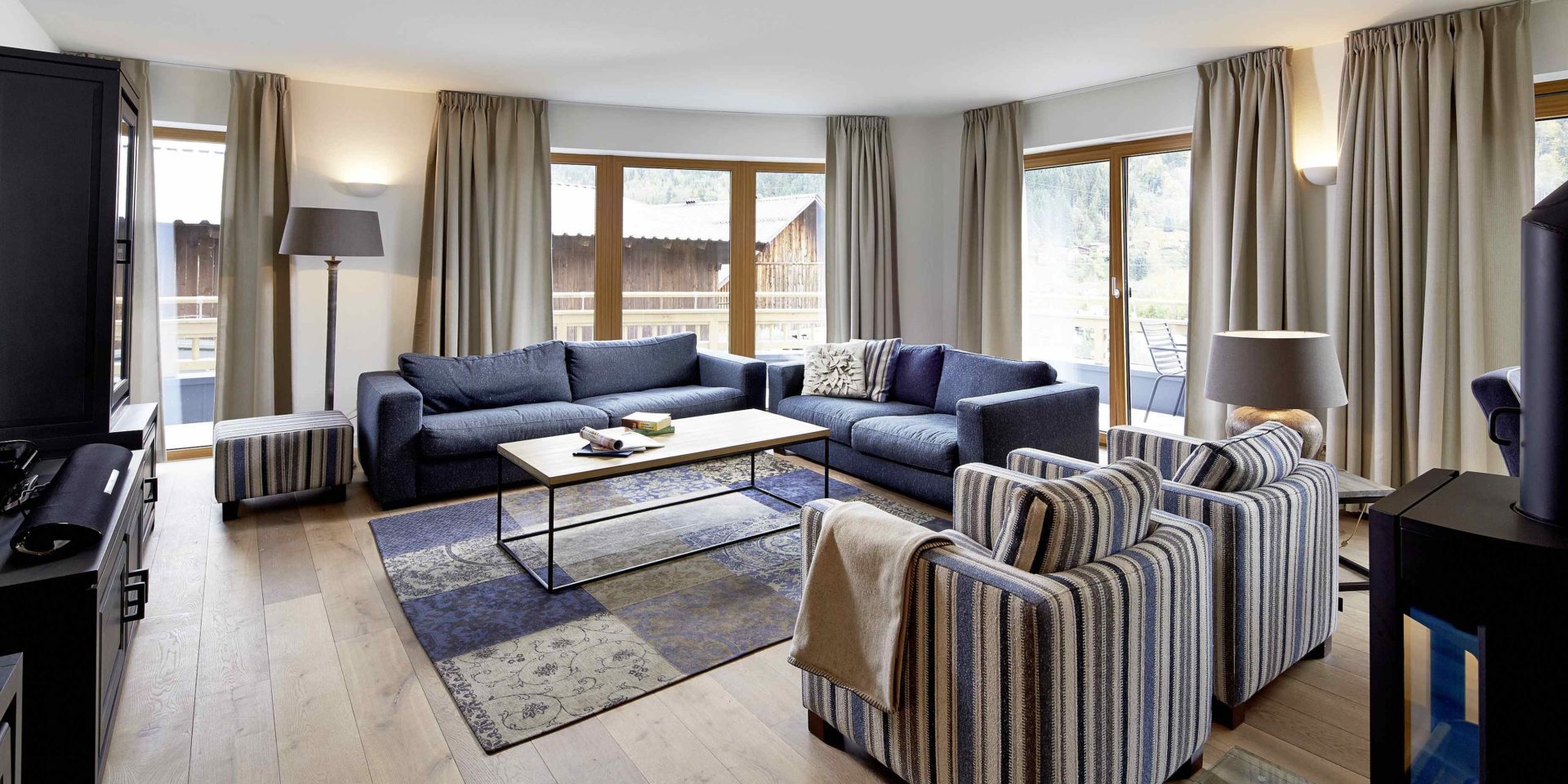 Kaprun Glacier Estate Zell am See-Kaprun Oostenrijk wintersport skivakantie luxe appartement K14 banken salontafel fauteuils hoge ramen kast vloerkleed houtkachel