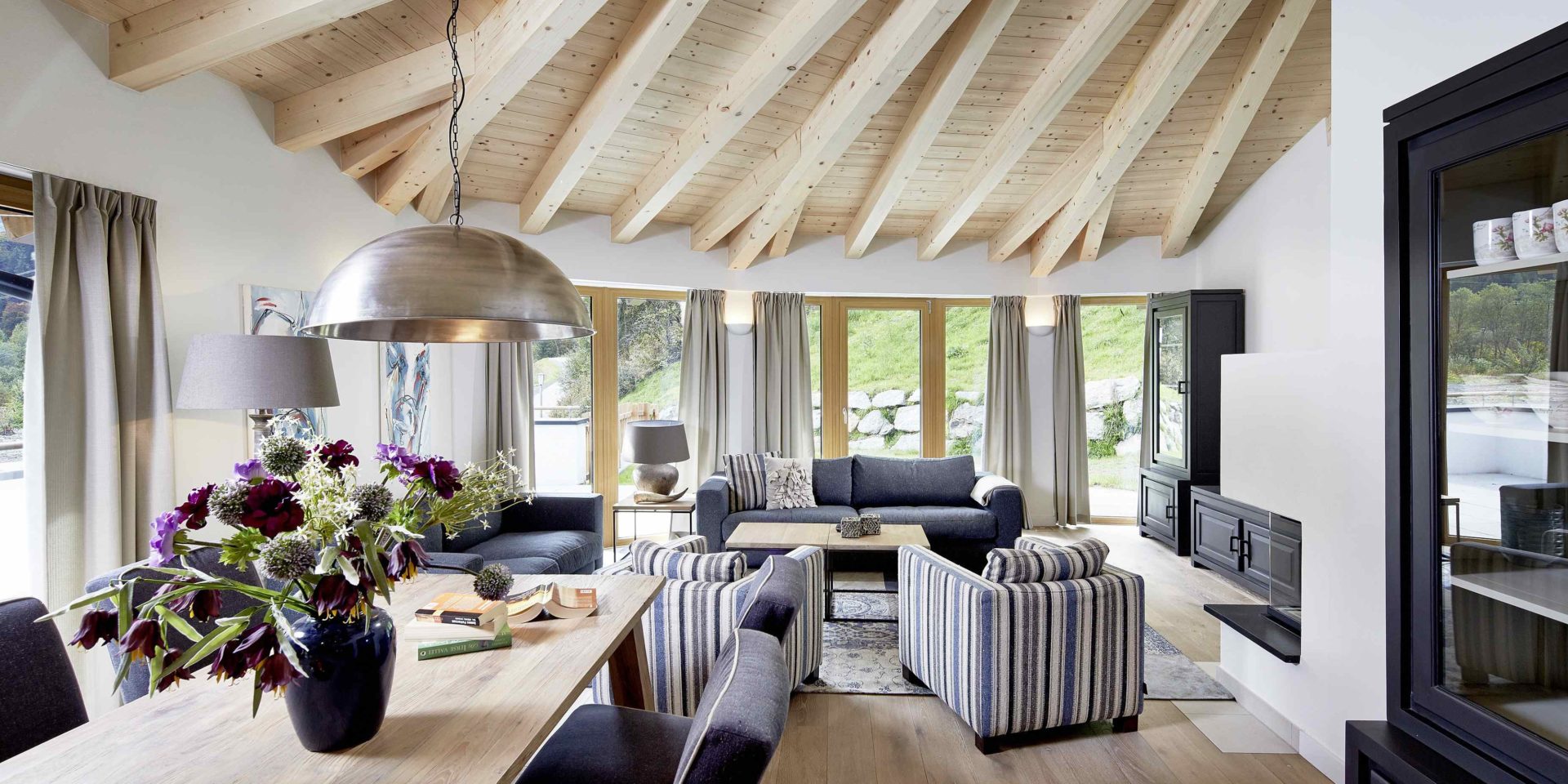 Kaprun Glacier Estate Zell am See-Kaprun Oostenrijk wintersport skivakantie luxe Penthouse K10 eettafel stoelen bloemen lamp banken fauteuils kasten grote ramen houten balken