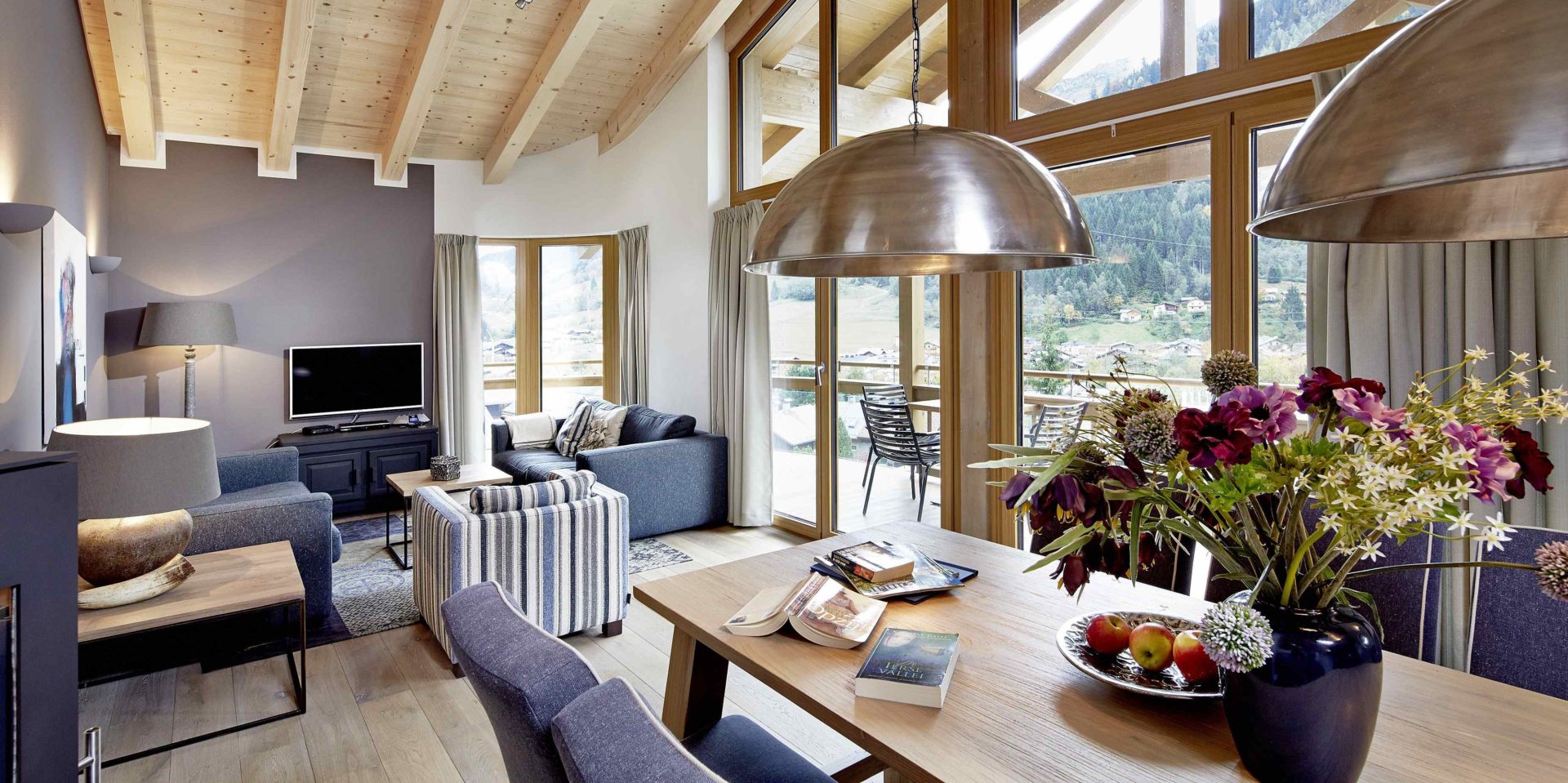 Kaprun Glacier Estate Zell am See-Kaprun Oostenrijk wintersport skivakantie luxe Penthouse K6 eettafel stoelen bloemen lampen banken fauteuil TV balkon stoelen bomen