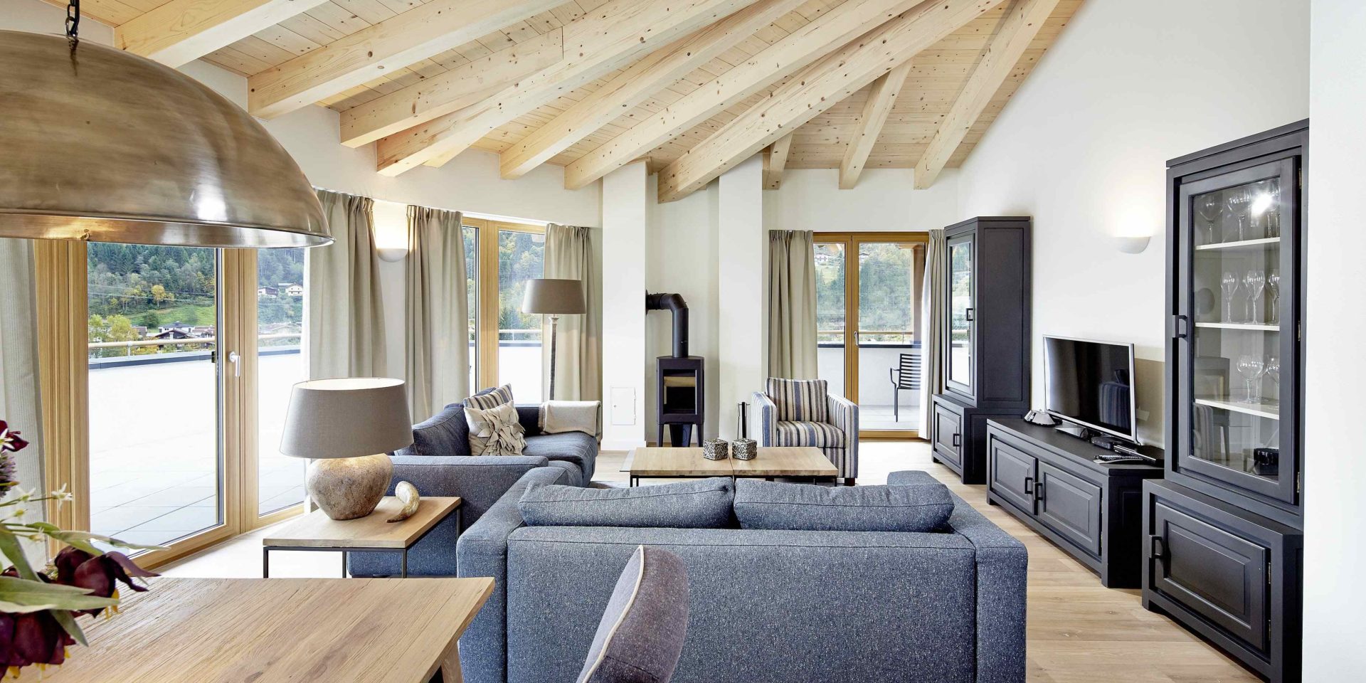Kaprun Glacier Estate Zell am See-Kaprun Oostenrijk wintersport skivakantie luxe Penthouse K8 eettafel lamp banken fauteuil TV kasten grote ramen houten balken