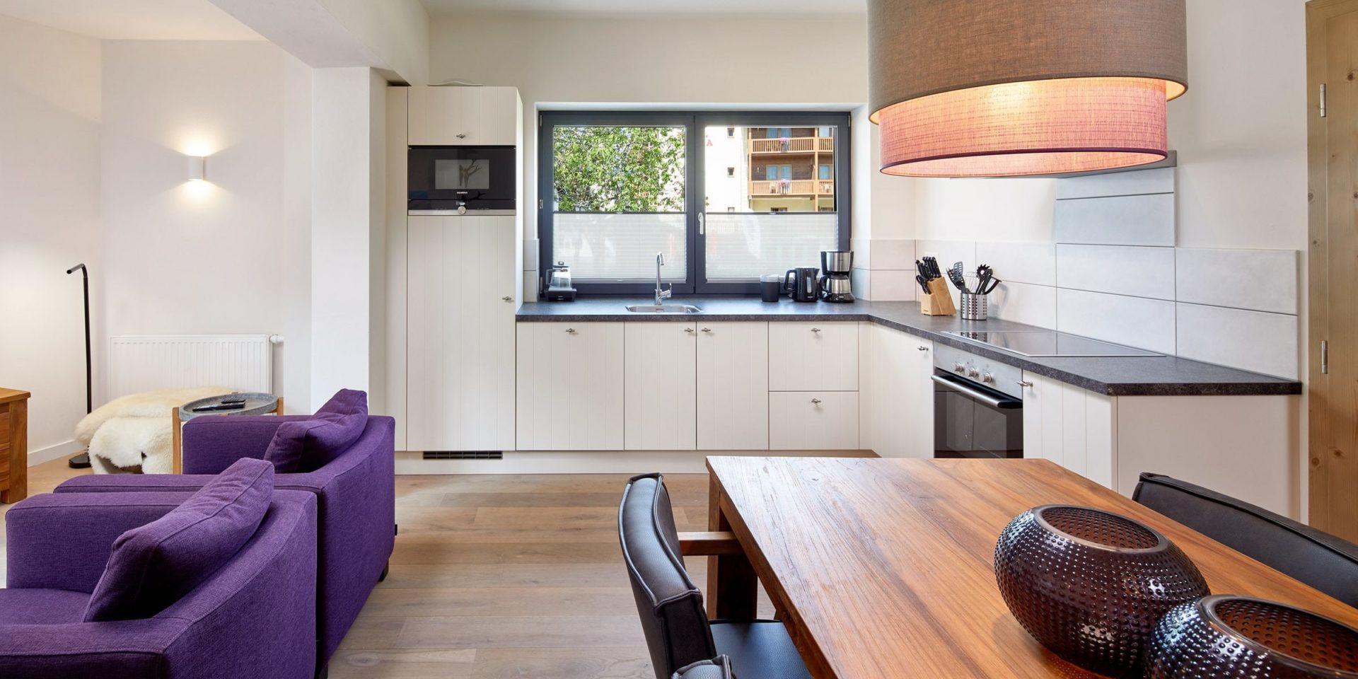 Kristall Plaza Niederau Wildschonau Oostenrijk wintersport skivakantie luxe appartement P6A eettafel stoelen lampen paarse fauteuils keuken raam