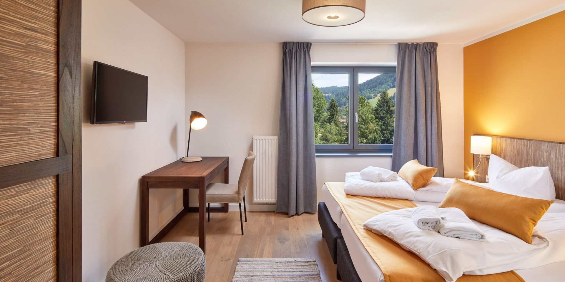 Kristall Plaza Niederau Wildschonau Oostenrijk wintersport skivakantie luxe appartement P4C slaapkamer aparte bedden bedsprei bureau stoel TV raam hocker gele muur lamp