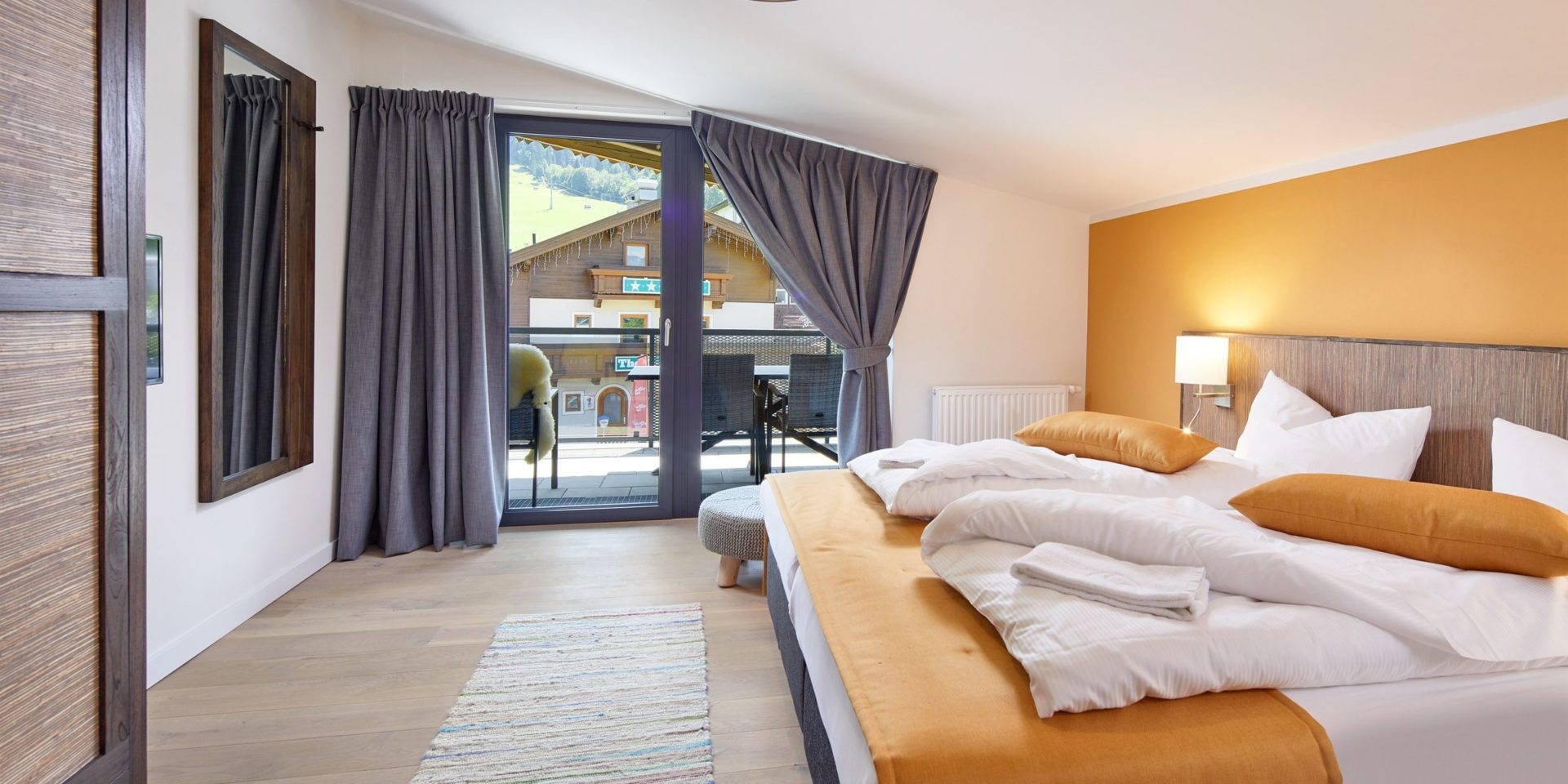 Kristall Plaza Niederau Wildschonau Oostenrijk wintersport skivakantie luxe appartement P8 slaapkamer aparte bedden bedsprei hoge ramen spiegel gele muur nachtlampje