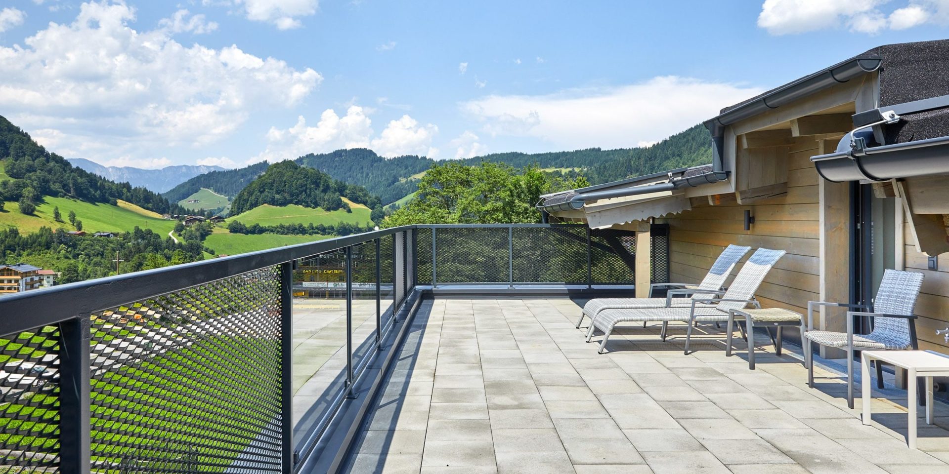 Kristall Plaza Niederau Wildschonau Oostenrijk wintersport skivakantie luxe appartement P8 terras ligstoelen tafeltje stoelen uitzicht bergen bomen