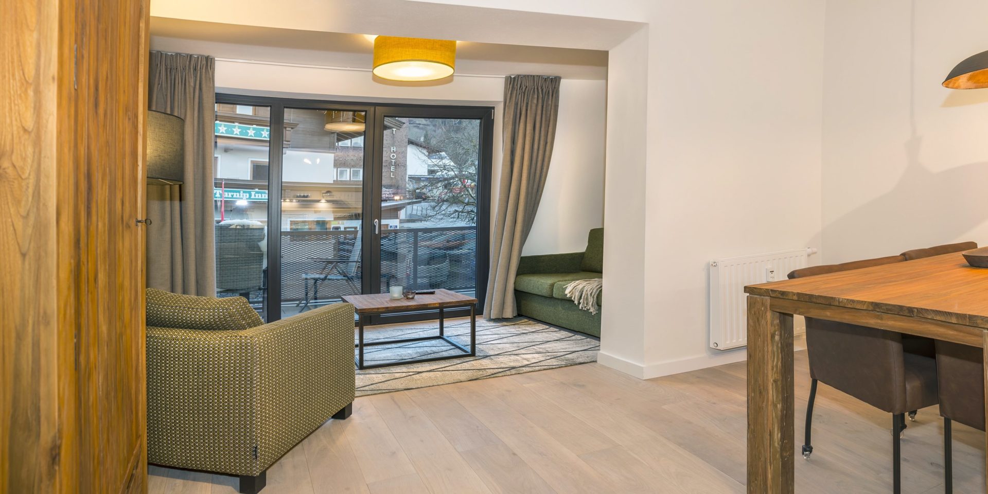 Kristall Plaza Niederau Wildschonau Oostenrijk wintersport skivakantie luxe appartement P4B groen bank fauteuil salontafel hoge ramen eettafel stoelen lampen balkon stoel