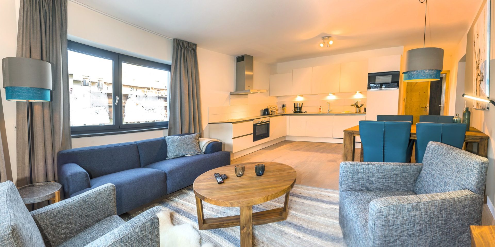 Kristall Plaza Niederau Wildschonau Oostenrijk wintersport skivakantie luxe appartement P4C blauwe bank fauteuils salontafel ramen eettafel stoelen lamp keuken