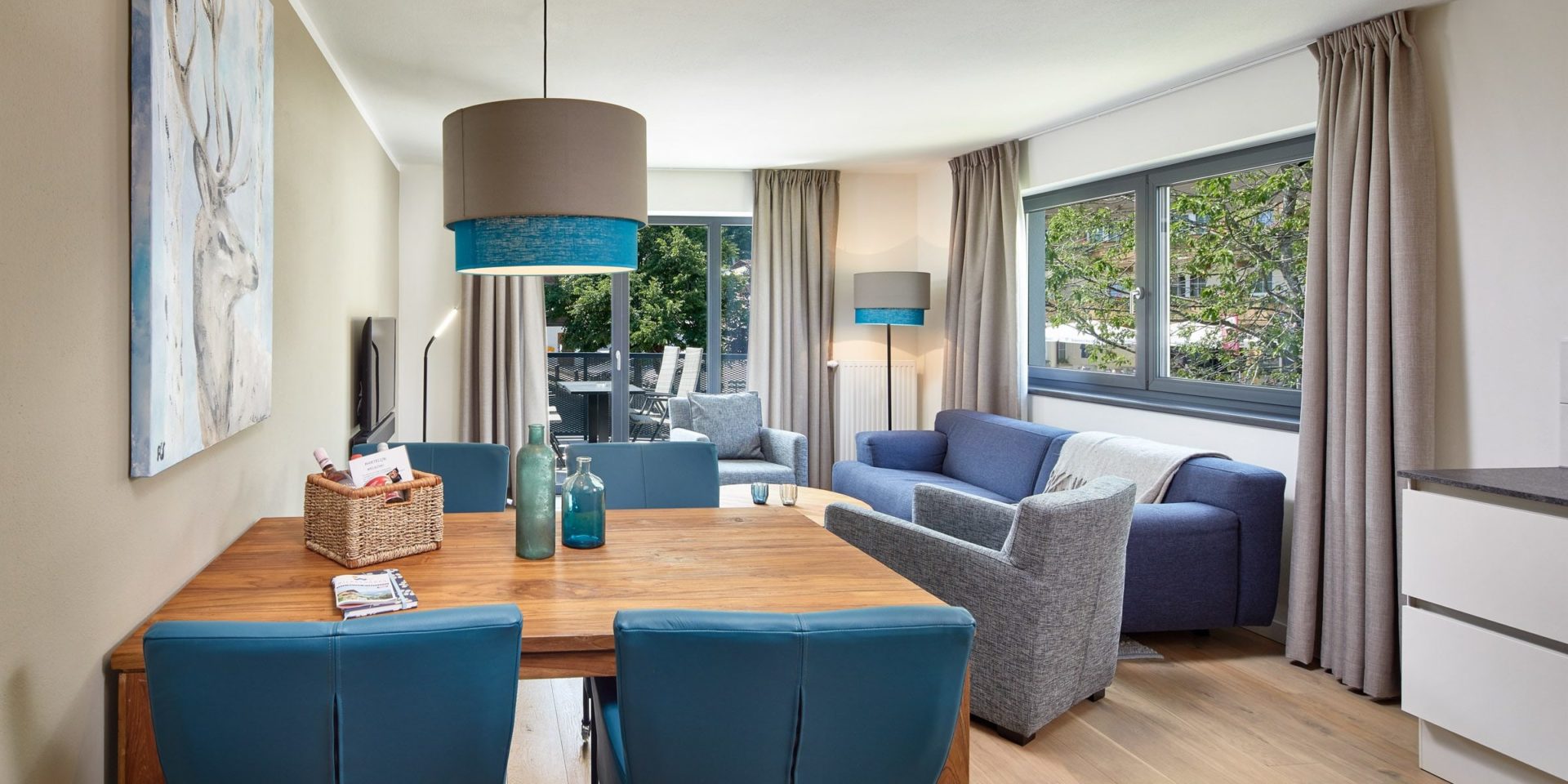 Kristall Plaza Niederau Wildschonau Oostenrijk wintersport skivakantie luxe appartement P4C blauwe bank fauteuils salontafel TV hoge ramen eettafel stoelen lamp schilderij hert keuken gordijnen