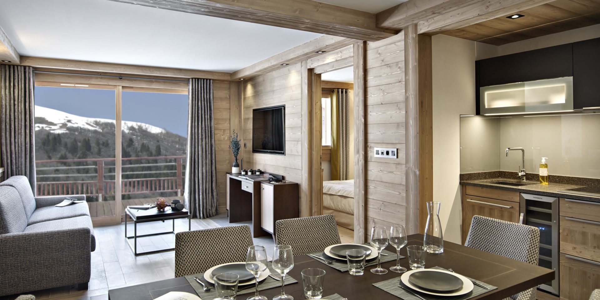 MGM Residence Anitea Valmorel Le Grand Domaine Frankrijk wintersport skivakantie luxe appartement eetkamer gedekte tafel stoelen keuken bank salontafel TV balkon uitzicht bed