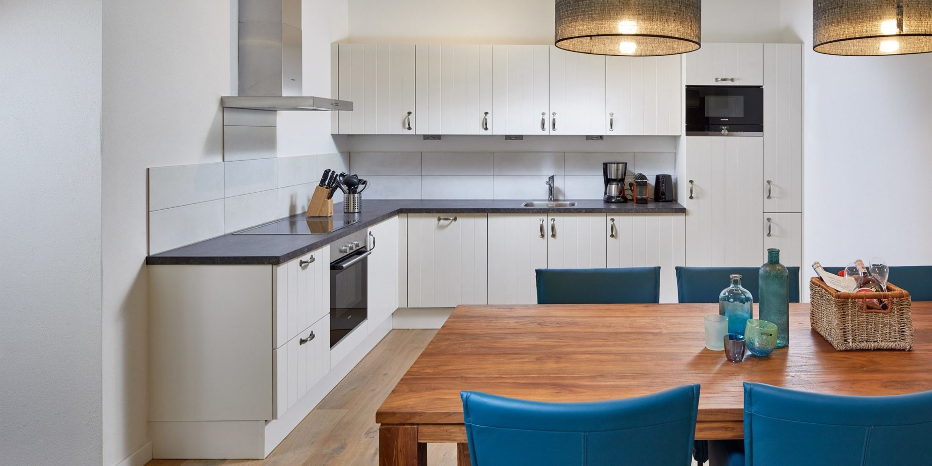 Residenz Drachenstein Niederau Wildschonau Oostenrijk wintersport skivakantie luxe appartement D4B eettafel blauwe stoelen welkomstpakket keuken messenblok lampen