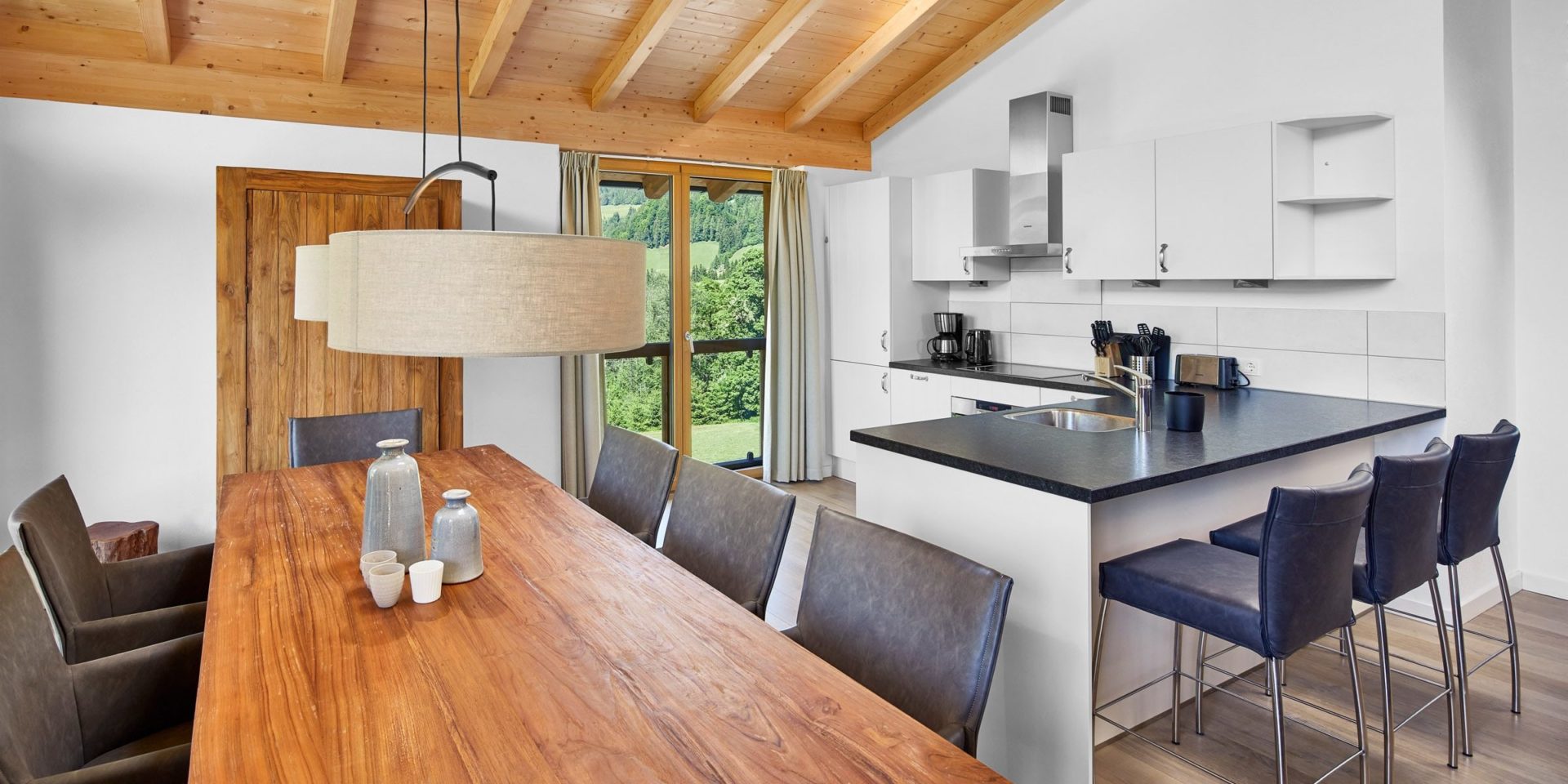 Residenz Drachenstein Niederau Wildschonau Oostenrijk wintersport skivakantie luxe appartement D8A eettafel stoelen lampen keuken eiland stoelen messenblok lampen hoge ramen houten balken