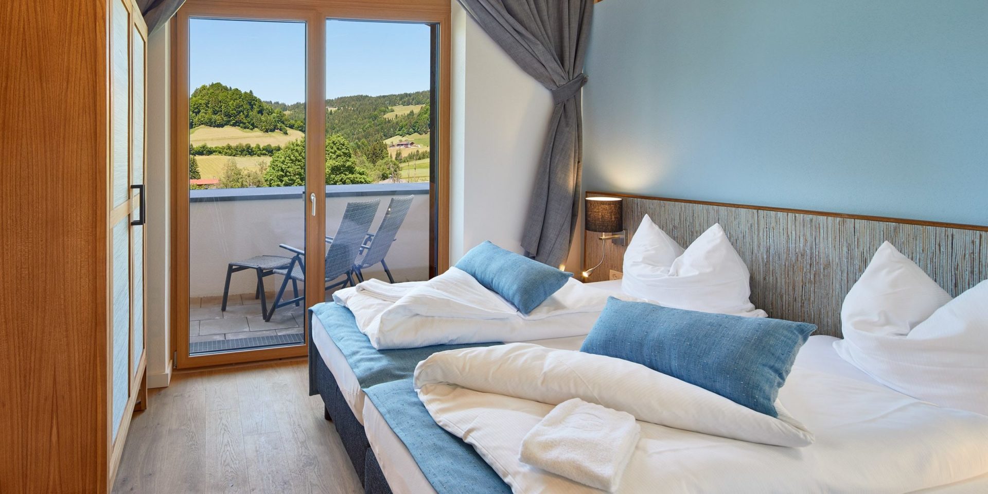 Residenz Drachenstein Niederau Wildschonau Oostenrijk wintersport skivakantie luxe slaapkamer D12 aparte bedden blauwe kussens blauwe muur kast balkon stoelen bomen