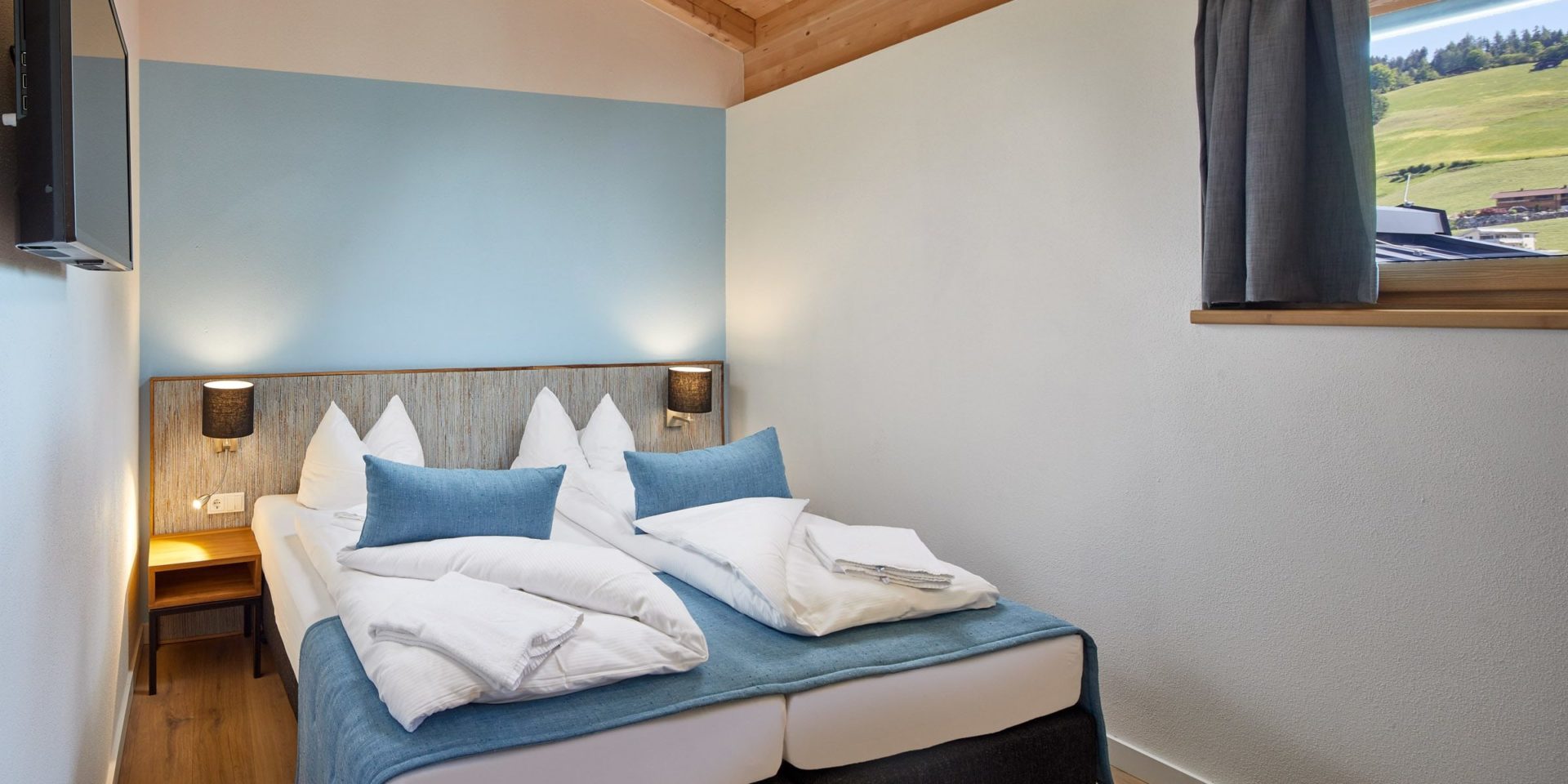 Residenz Drachenstein Niederau Wildschonau Oostenrijk wintersport skivakantie luxe slaapkamer D8B aparte bedden blauwe kussens blauwe muur TV raam nachtlampjes