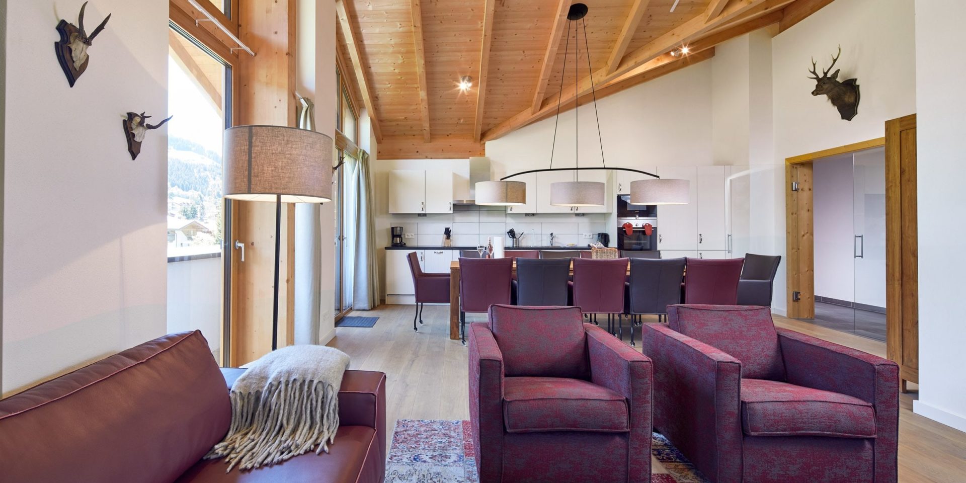 Residenz Drachenstein Niederau Wildschonau Oostenrijk wintersport skivakantie luxe appartement D12 paarse bank fauteuils vloerkleed eettafel paarse stoelen keuken hert hoge ramen houten balken