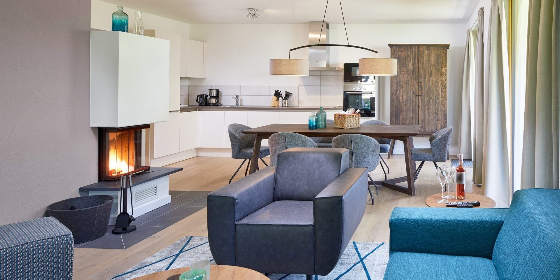 Residenz Drachenstein Niederau Wildschonau Oostenrijk wintersport skivakantie luxe appartement D6 blauwe bank fauteuil open haard hocker eettafel stoelen lampen keuken kast