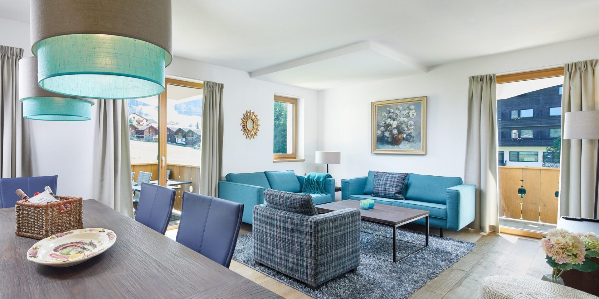Residenz Drachenstein Niederau Wildschonau Oostenrijk wintersport skivakantie luxe appartement D6 blauwe banken fauteuil salontafel eettafel stoelen welkomstpakket vloerkleed lampen balkon zitje