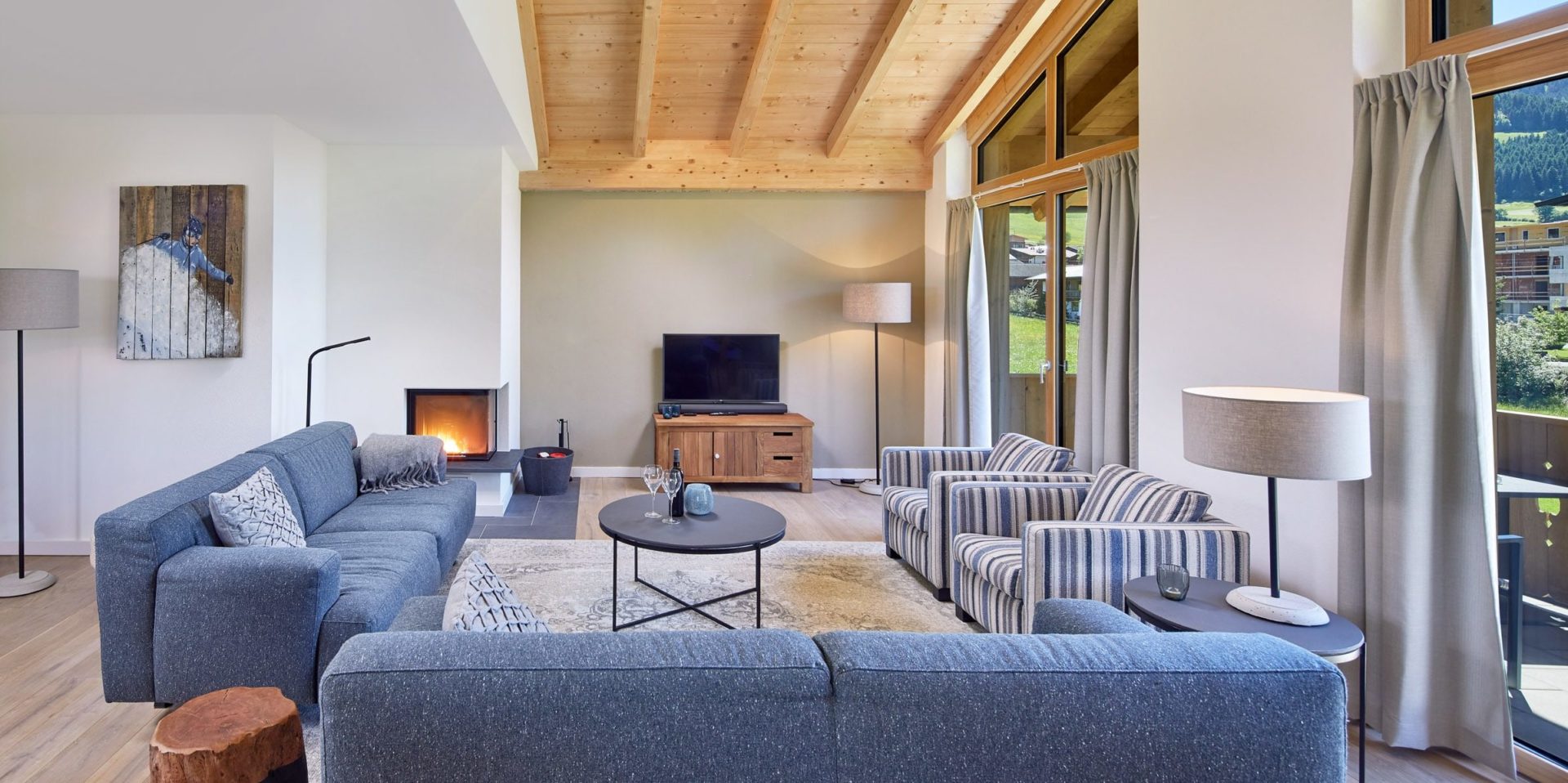 Residenz Drachenstein Niederau Wildschonau Oostenrijk wintersport skivakantie luxe appartement D8A grijze banken fauteuils salontafel TV open haard vloerkleed balkon zitje hoge ramen houten balken