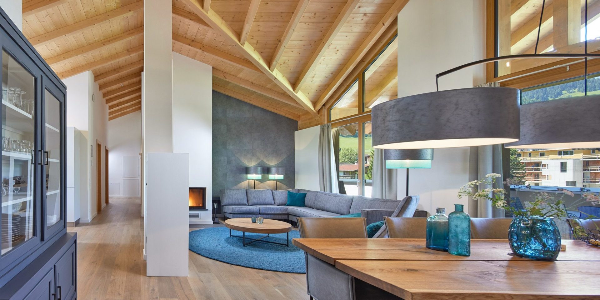Residenz Drachenstein Niederau Wildschonau Oostenrijk wintersport skivakantie luxe appartement D8B grijze hoekbank fauteuil salontafel open haard vloerkleed kast hoge ramen houten balken