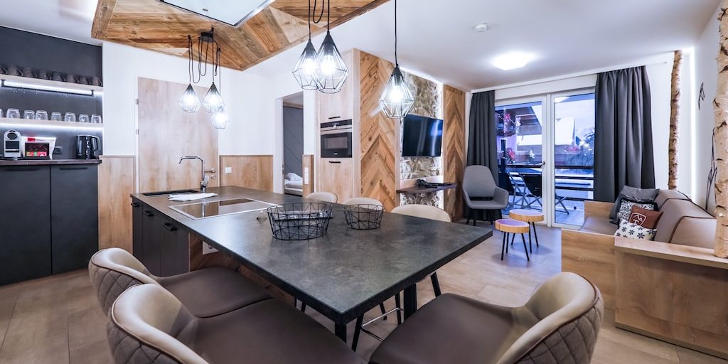 Hotel 24 by Avenida Kaprun Zell am See-Kaprun Oostenrijk wintersport skivakantie luxe 1 slaapkamer suite 2 personen living kookeiland barkrukken bank kussens fauteuil salontafels TV balkon ligstoelen