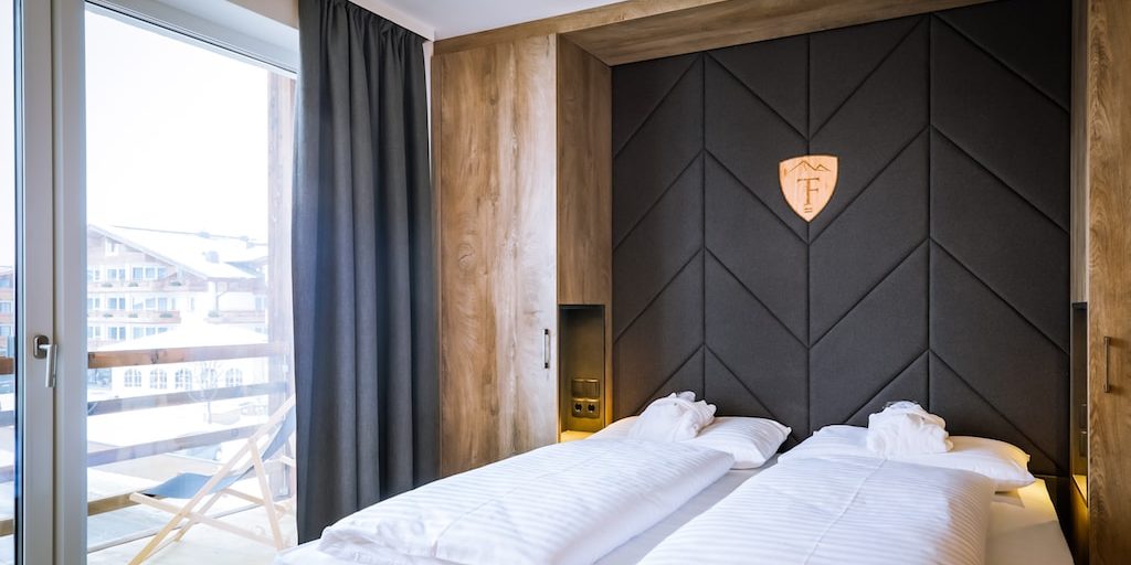 Hotel 24 by Avenida Kaprun Zell am See-Kaprun Oostenrijk wintersport skivakantie luxe 2-persoonskamer slaapkamer 24 2-persoonsbed hoofdbord houten kastenwand balkon ligstoel raam