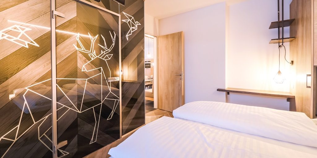 Hotel 24 by Avenida Kaprun Zell am See-Kaprun Oostenrijk wintersport skivakantie luxe 3-slaapkamer suite slaapkamer 2-persoonsbed kastenwans hert vogels hanglamp
