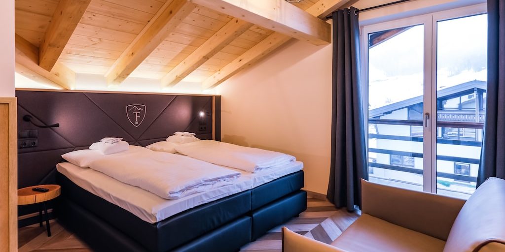 Hotel 24 by Avenida Kaprun Zell am See-Kaprun Oostenrijk wintersport skivakantie luxe Penthouse 3 slaapkamers slaapkamer 2-persoonsbed fauteuil houten balken balkon krukje