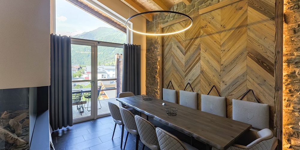 Hotel 24 by Avenida Kaprun Zell am See-Kaprun Oostenrijk wintersport skivakantie luxe Penthouse 4 slaapkamers eetkamer eettafel stoelen kussens houten wand open haard balkon tafel stoelen