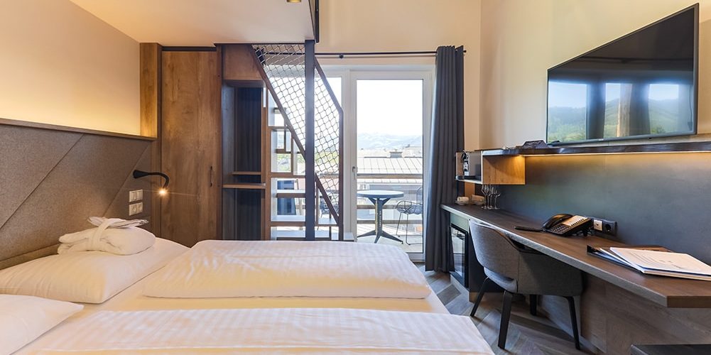 Hotel 24 by Avenida Kaprun Zell am See-Kaprun Oostenrijk wintersport skivakantie luxe Penthouse 4 slaapkamers slaapkamer 2-persoonsbed bureau stoel TV balkon zitje tafel stoelen