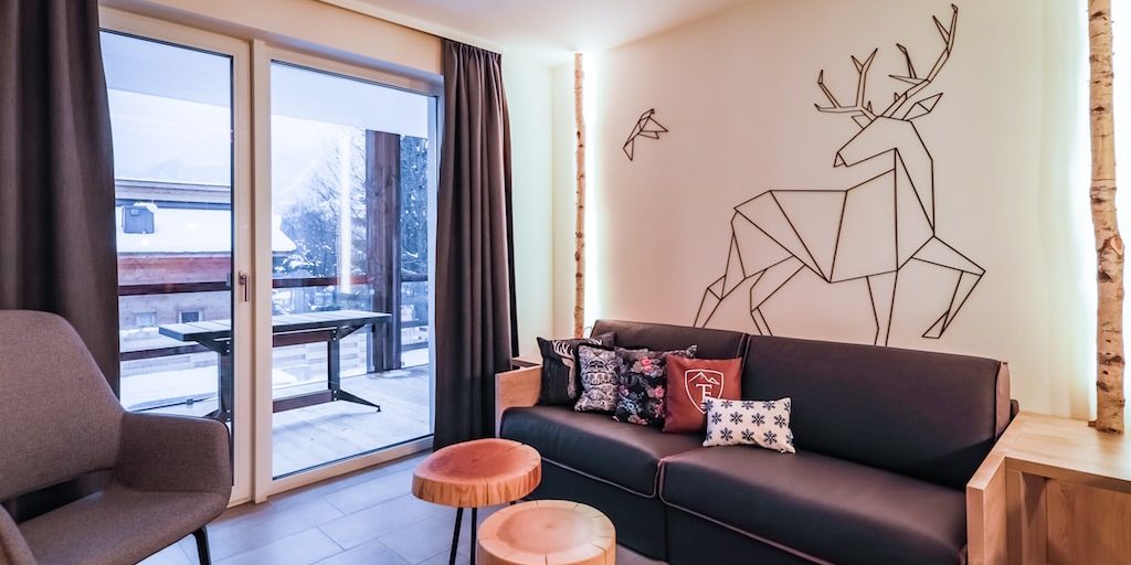 Hotel 24 by Avenida Kaprun Zell am See-Kaprun Oostenrijk wintersport skivakantie luxe Studio living bank kussens krukjes fauteuil hert vogel balkon tafel boomstammen