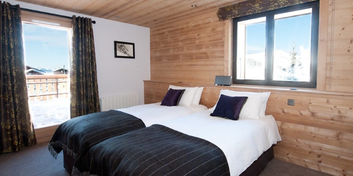 Altitude Lodge Les Gets les Portes du Soleil Frankrijk wintersport skivakantie luxe slaapkamer aparte bedden paarse kussens houten wand raam balkon schilderij