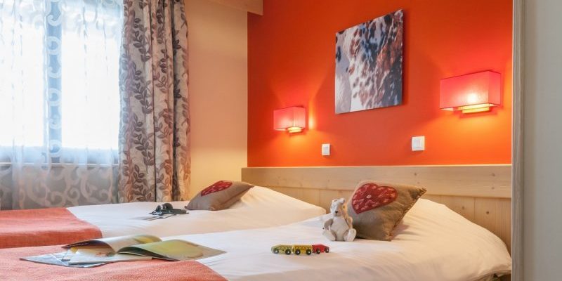 Residence l'Amara Avoriaz Les Portes du Soleil Frankrijk wintersport skivakantie luxe slaapkamer aparte bedden oranje muur schilderij wandlampen kussens beer boeken auto's raam