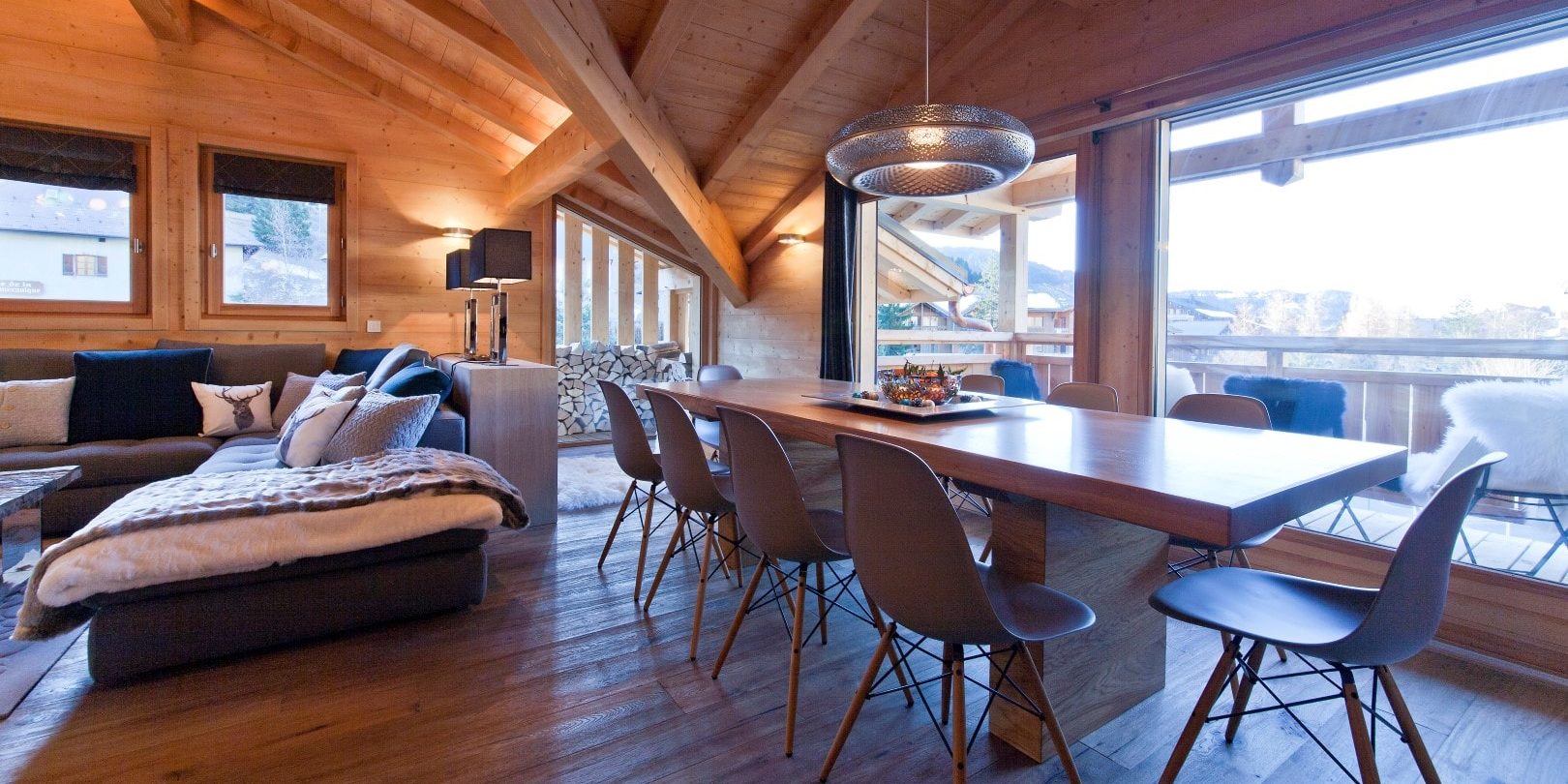 Appartement No. 5 Les Gets Les Portes du Soleil Frankrijk wintersport skivakantie luxe eetkamer eettafel stoelen loungebank chaise longue kussens hanglamp hout houten balken balkon stoelen uitzicht bomen sneeuw