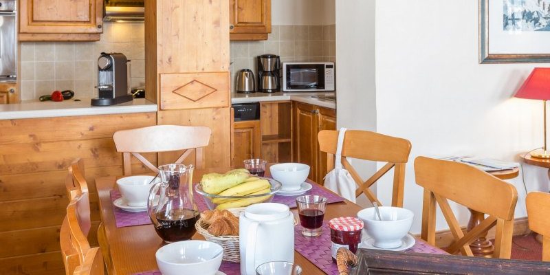 Arc 1950 le Village Arc 1950 Paradiski Frankrijk wintersport skivakantie luxe appartement Prince des Cimes gedekte tafel ontbijt croissants houten stoelen keuken schilderij hout